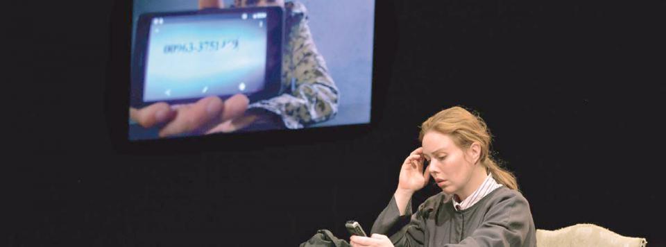 Szene aus dem Theaterstück „Undercover Dschihadistin“ mit einer jungen Frau, die ihr Handy bedient.