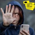 Eine Jugendliche zeigt das "Stopp"-Zeichen, in der anderen Hand hält sie ein Smartphone